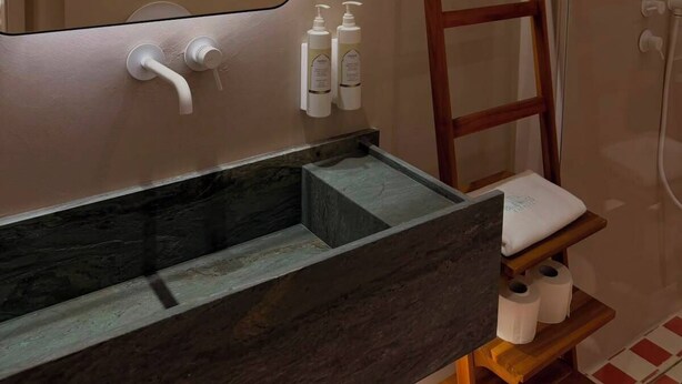 A bathroom with a modern sink, a mirror, a wooden ladder, and toiletries on a shelf. - Bluewaves Antiparos Sunstone Terrace House (ANTIPAROS)