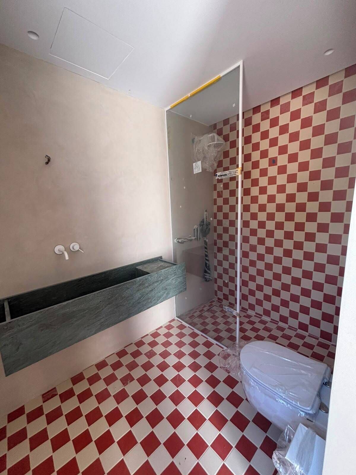 A bathroom with a checkered floor, a sink with a mirror, and a toilet.