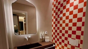 Un baño con piso a cuadros, un lavamanos con espejo y un inodoro.