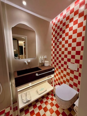 A bathroom with a checkered floor, a sink with a mirror, and a toilet.
