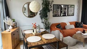 Een moderne woonkamer met een houten eettafel, een bank en een grote spiegel.