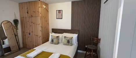 Une chambre à coucher avec un lit, une armoire en bois, une chaise et un tableau accroché au mur.
