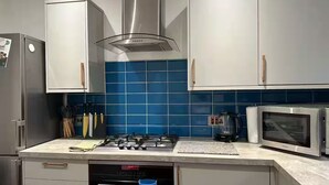 Een moderne keuken met roestvrijstalen apparatuur, een blauwe tegelachtergrond en witte kastjes.