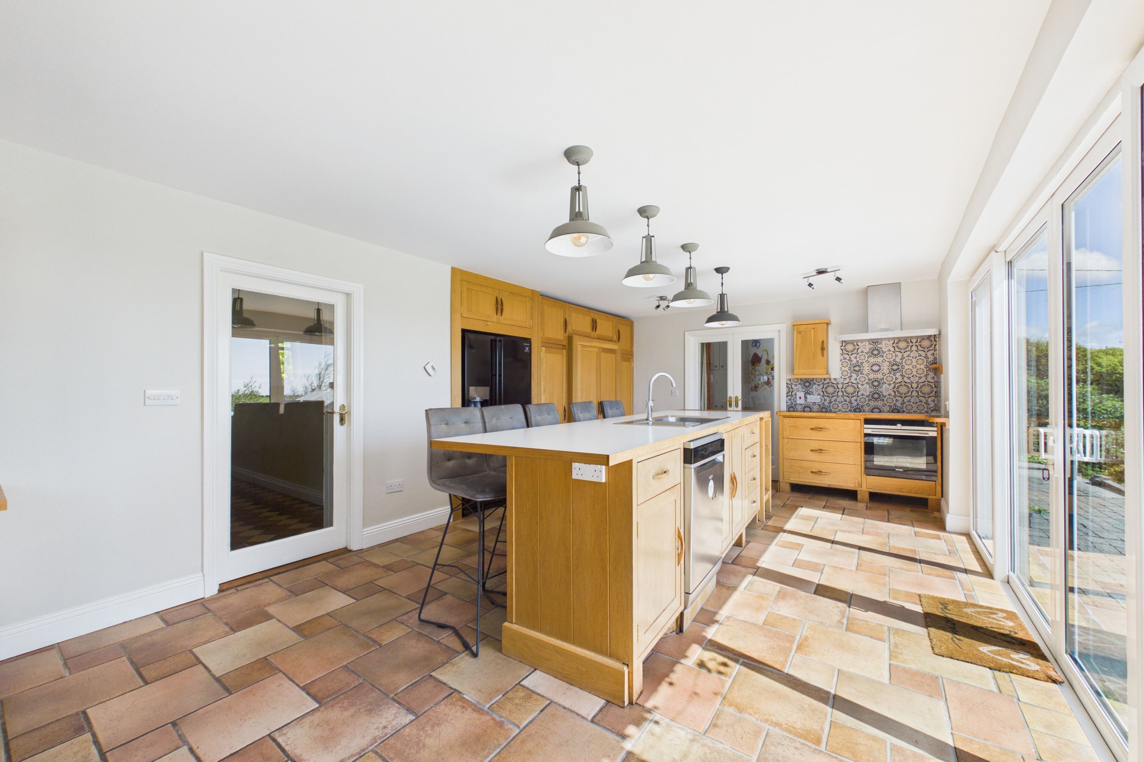 A modern kitchen with a central island, wooden cabinets, and a large window.