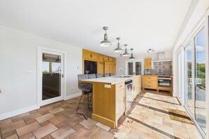 Een moderne keuken met een centraal eiland, houten kastjes en een groot raam.