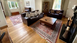 A living room with a brown leather sofa, a wooden coffee table, and a patterned rug. - 5 Bedroom Country House in Waterford (Waterford)