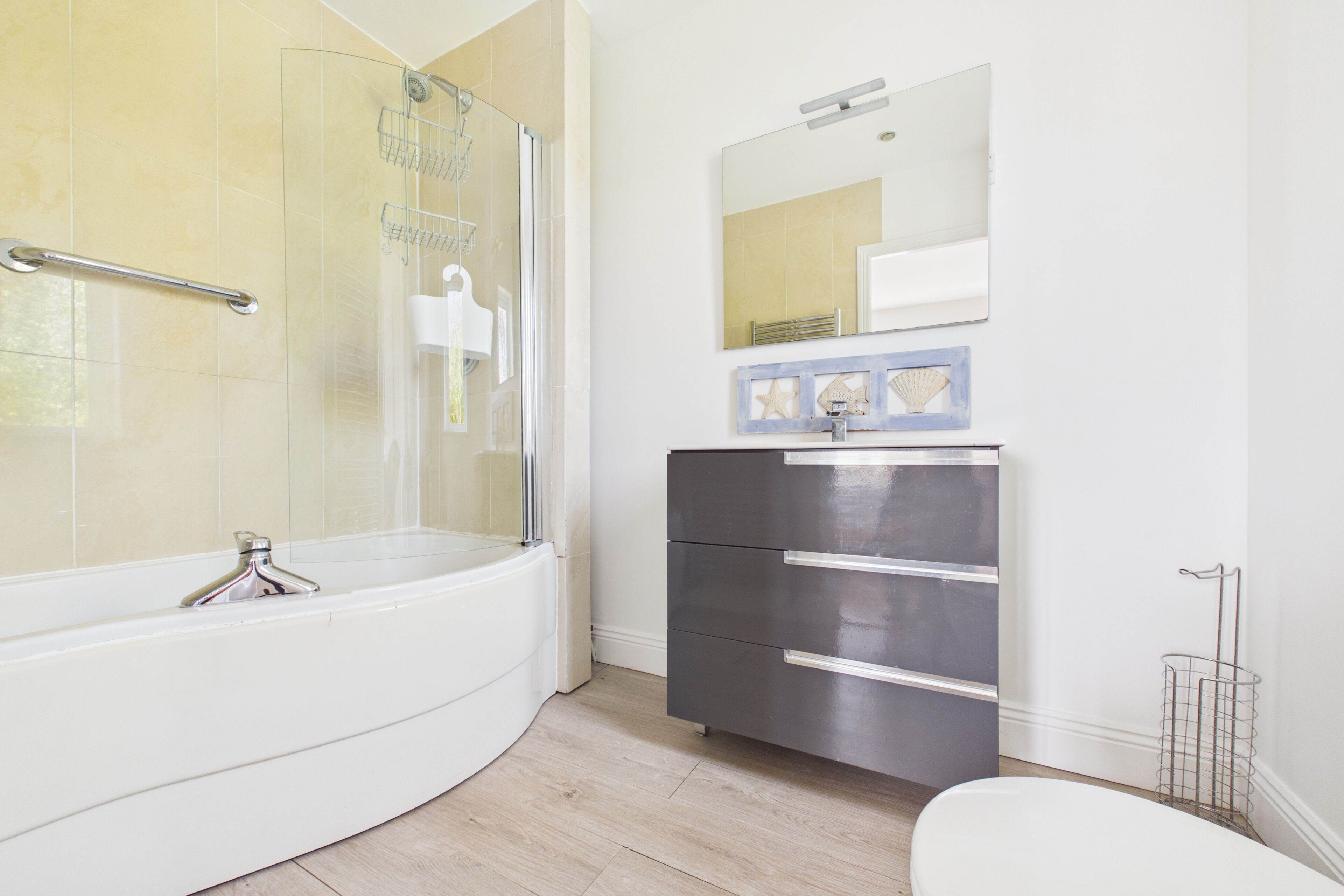 A modern bathroom with a freestanding bathtub, a glass-enclosed shower, a vanity with a mirror, and a toilet.