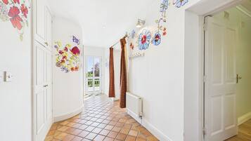 A hallway with tiled flooring, white walls, and floral wall art.