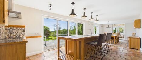 A modern kitchen with a large island, bar stools, and a view of the outdoors.