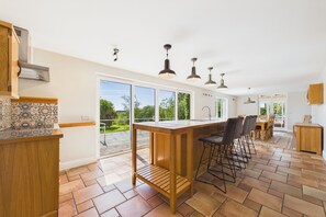 A modern kitchen with a large island, bar stools, and a view of the outdoors.