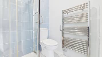 A modern bathroom with a glass shower enclosure, a white toilet, and a chrome towel rack.