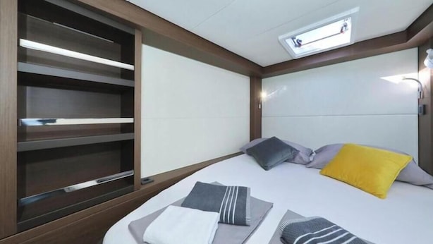 Une chambre à coucher moderne avec un lit, des oreillers, une table de chevet et une étagère intégrée.