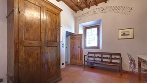 Una habitación con un armario de madera grande, un banco, una ventana con vistas y un cuadro colgado en la pared.