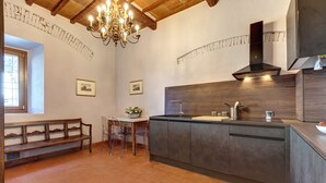 Una cocina con un banco de madera, sillas traslúcidas, una mesa de comedor, una araña y una estufa moderna.