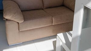 En beige sofa i et rum med hvide vægge, et billede og et vindue.