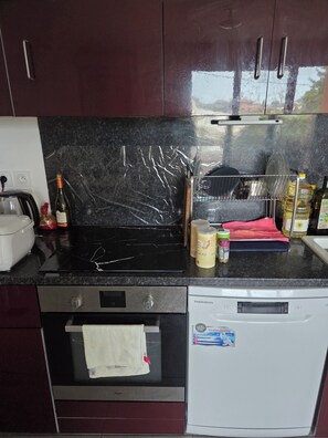 A kitchen with a black countertop, a dishwasher, an oven, and cabinets. - Accommodation near Lyon Airport, 15 minutes away, room (La Verpillière)