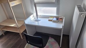 A compact office space with a desk, chair, and shelving unit. - Accommodation near Lyon Airport, 15 minutes away, room (La Verpillière)