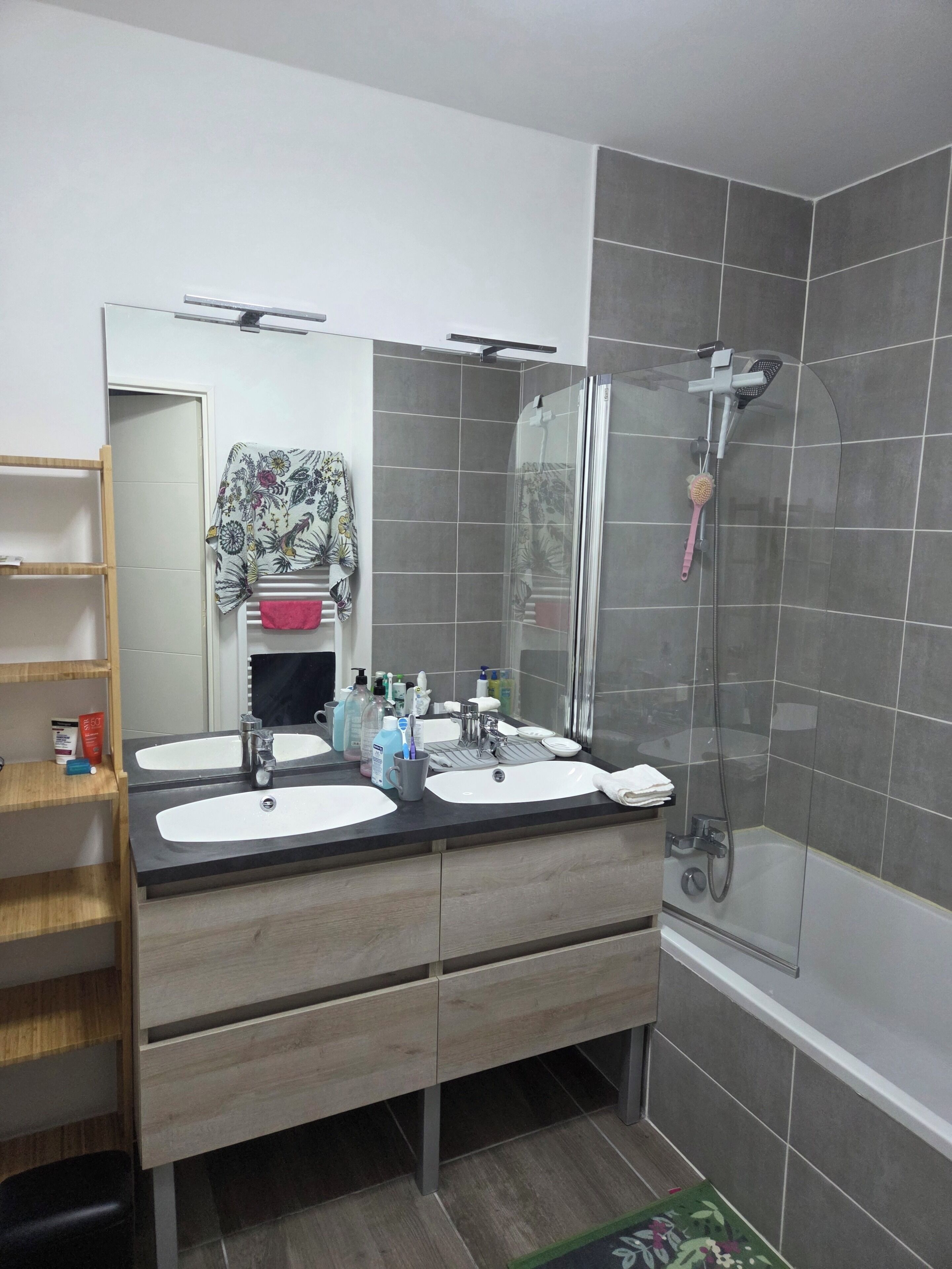 A bathroom with two sinks, a mirror, a shower, and a towel rack.