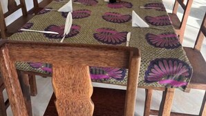 A dining area with a table set for six, surrounded by wooden chairs.