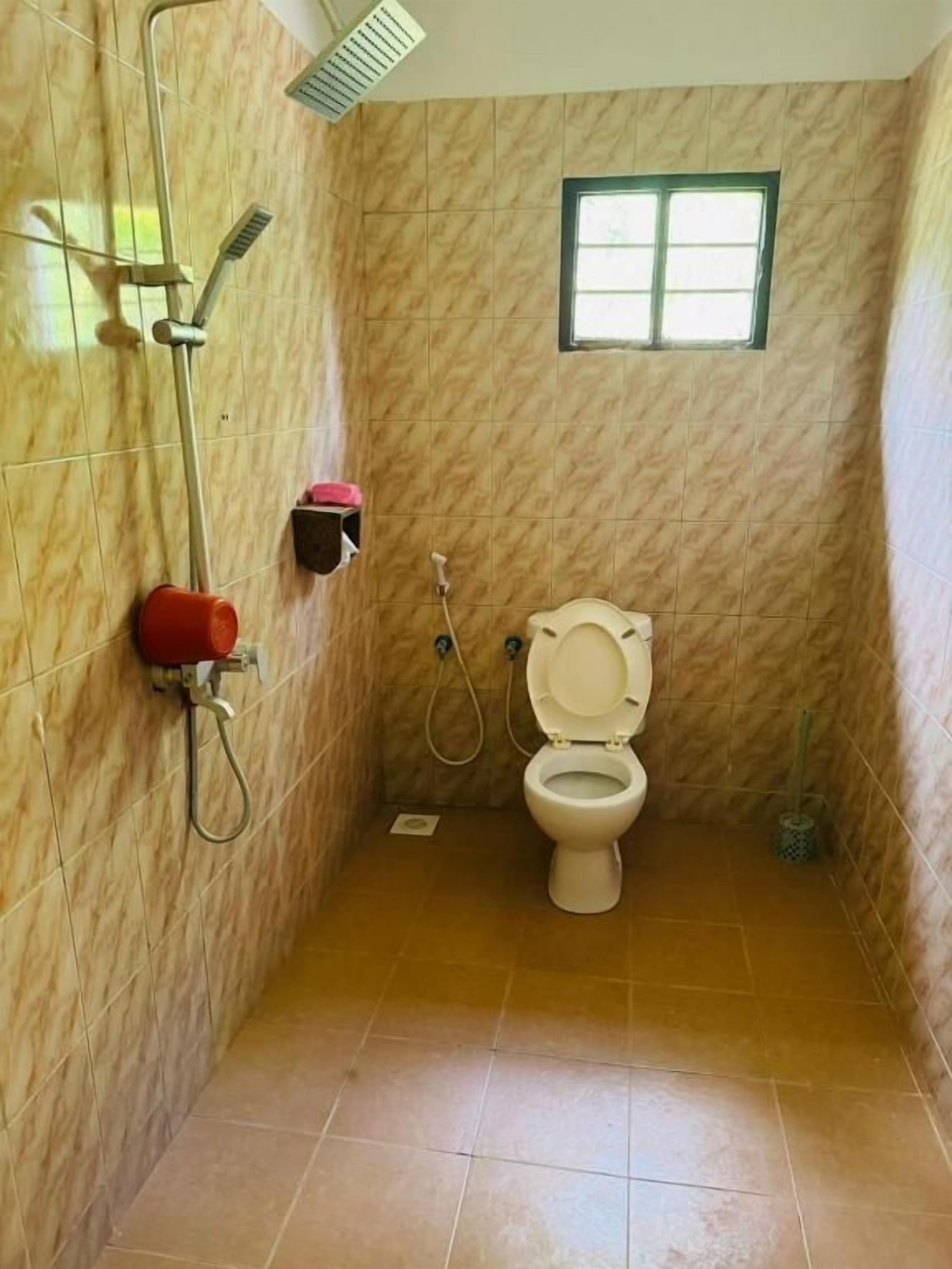 Une salle de bain avec des toilettes, une douche et une fenêtre.