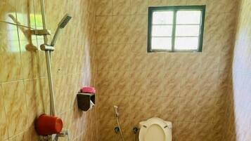 Une salle de bain avec des toilettes, une douche et une fenêtre.