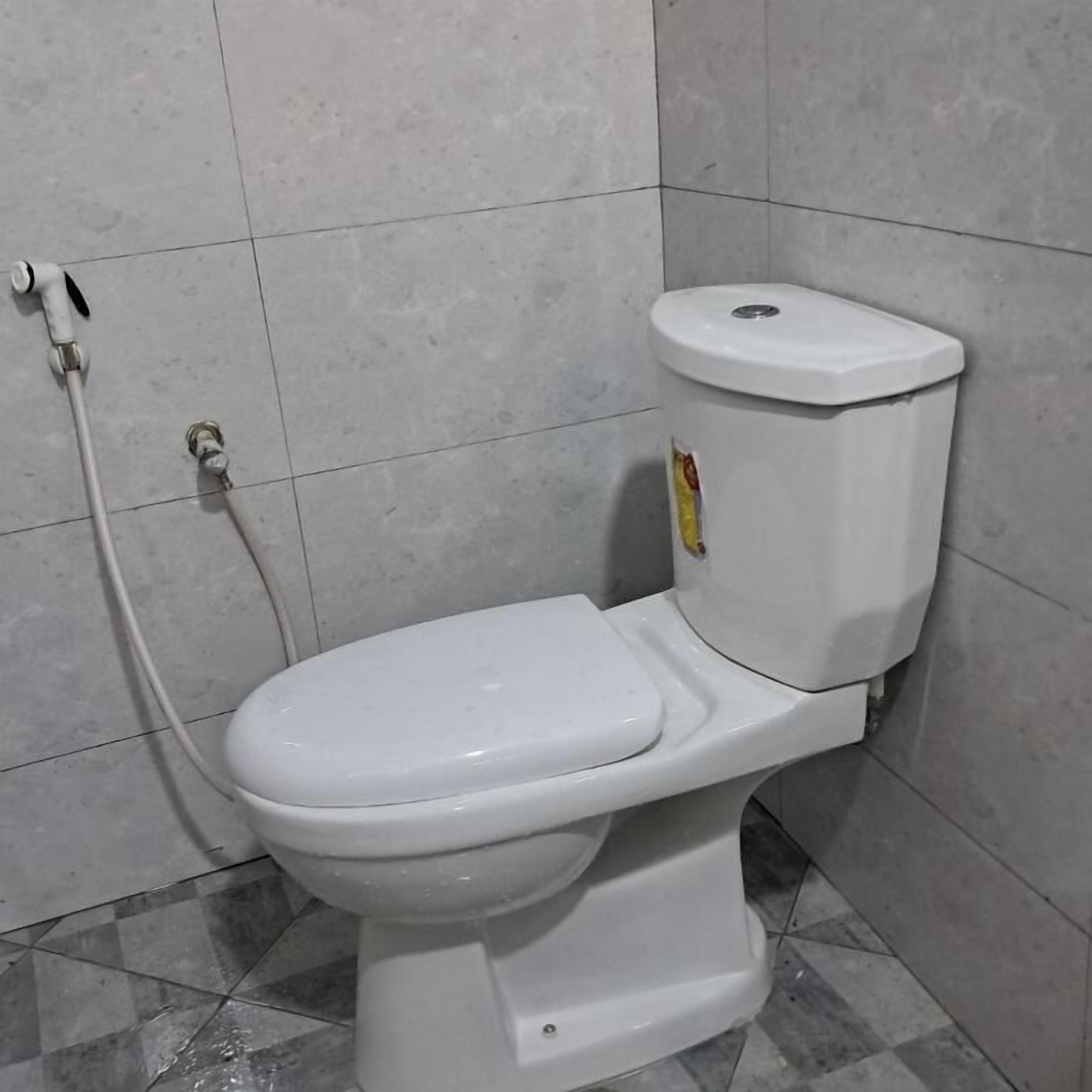 A white toilet with a bidet attachment in a tiled bathroom.