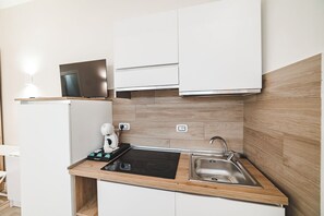 A compact kitchen with a built-in stove, a sink, and a microwave. - Comfort, Relaxation, and a Jacuzzi Just a Stone's Throw from the Heart of Rome (Roma)