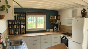 Eine Küche mit einer Holzausziehtheke, weißen Schränken, einem eingebauten Backofen und einem Kühlschrank.
