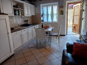 A kitchen with white cabinets, a dining table with chairs, and a red couch. - House in Banyuls-sur-Mer, on a quiet and beautiful pedestrian street 150 meters from the beach (Banyuls-sur-Mer)