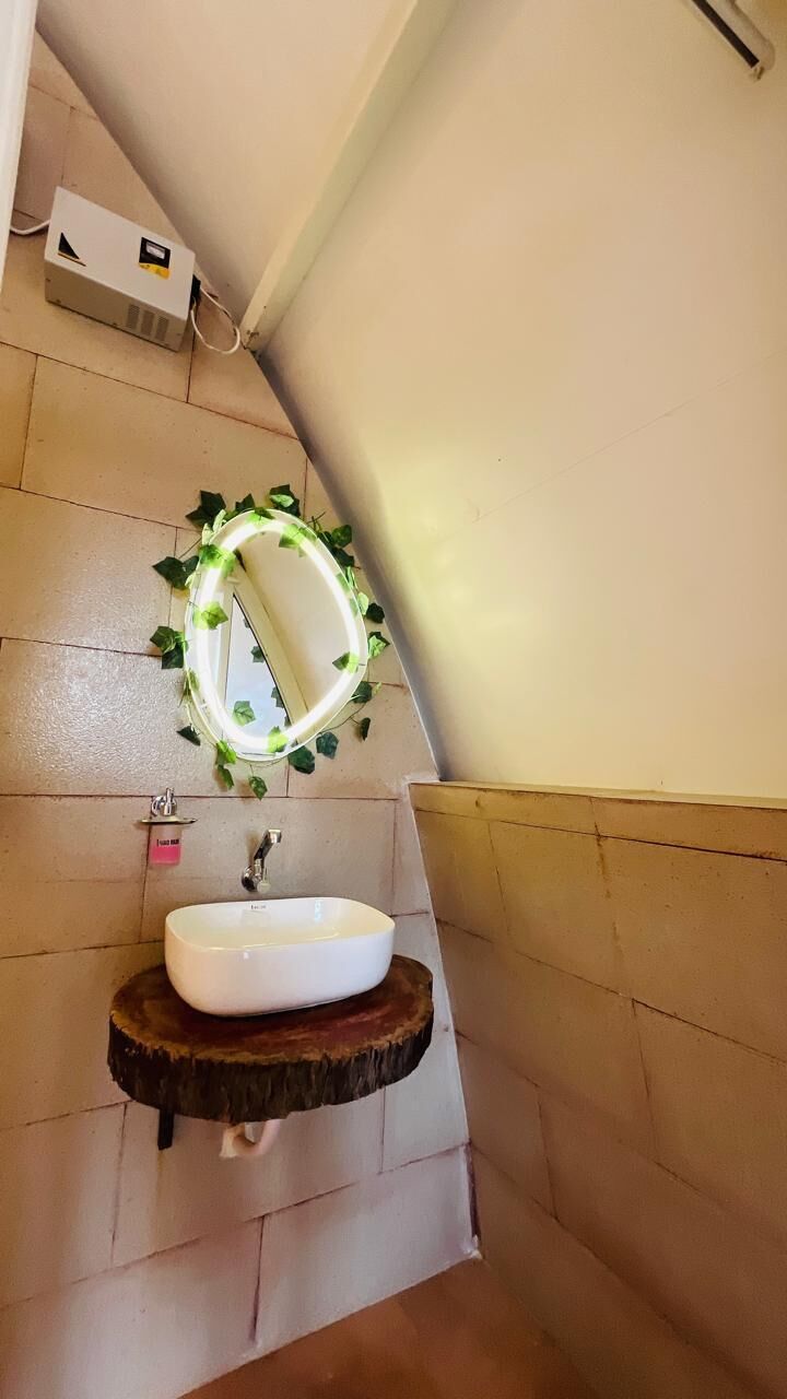 A bathroom with a white sink on a wooden base, a mirror with green foliage, and a towel rack.