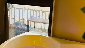 A bathtub with a view of a balcony and a table outside.