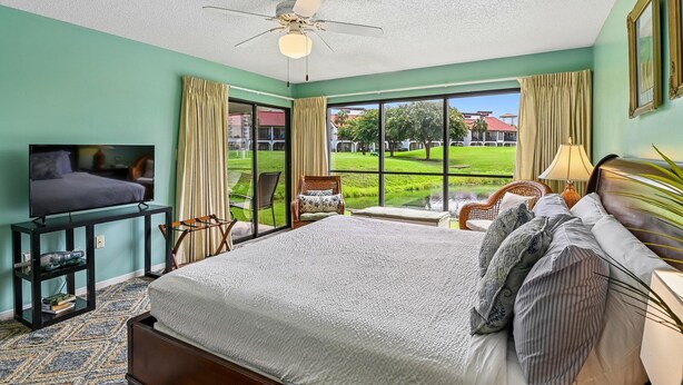 Una camera d'albergo con un letto, una televisione, una scrivania e vista su un campo da golf.