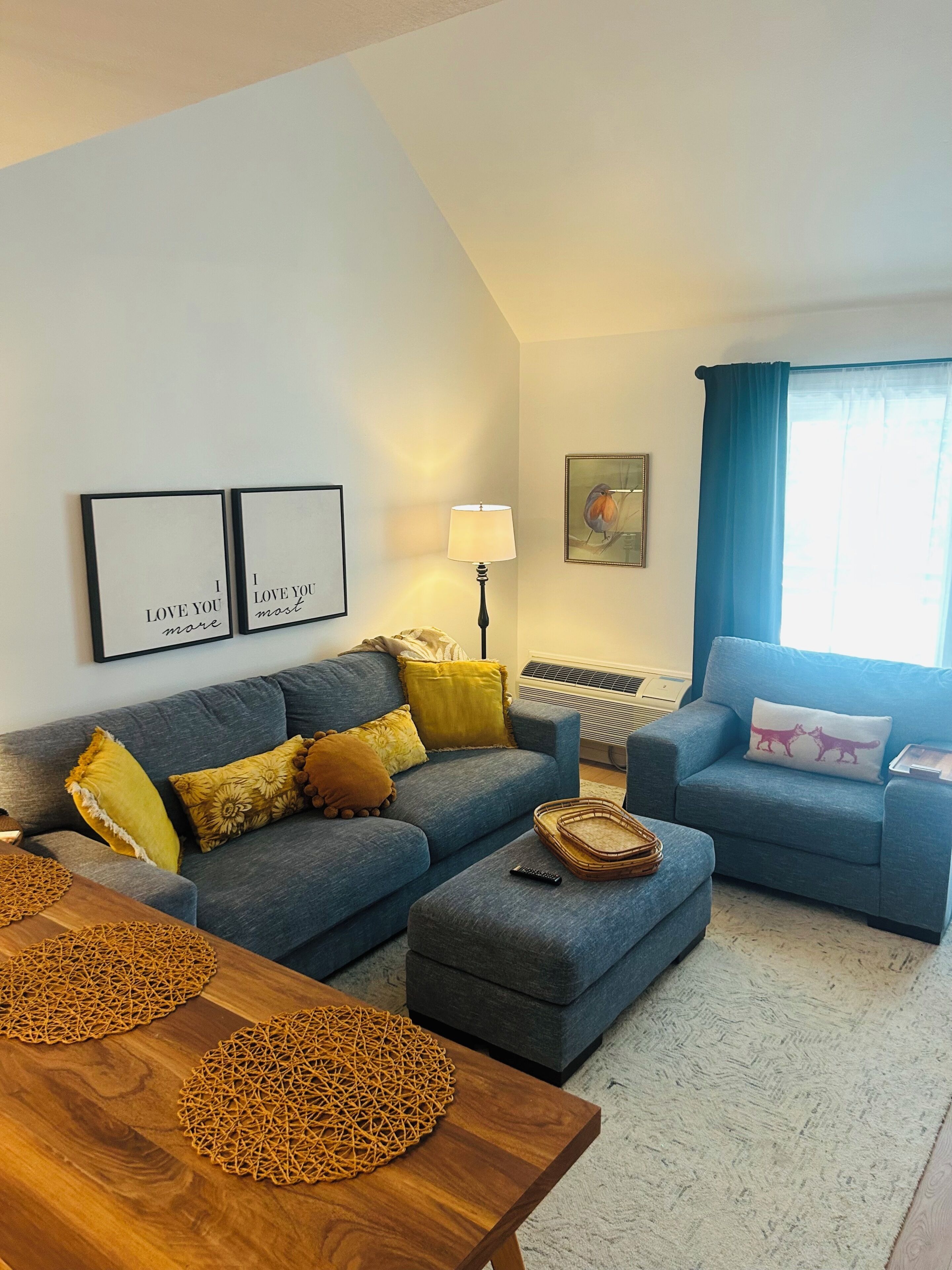 A living room with a grey sofa, a blue armchair, a wooden coffee table, and a lamp.