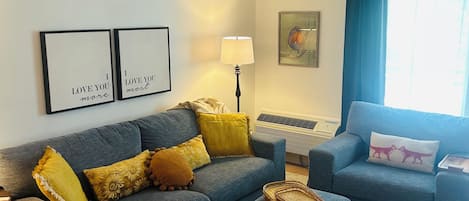 A living room with a grey sofa, a blue armchair, a wooden coffee table, and a lamp.
