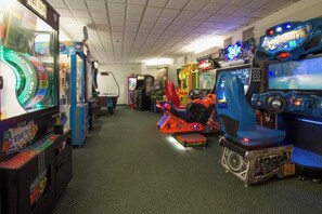 Une salle d’arcade proposant divers jeux, notamment un simulateur de moto et des jeux de course.