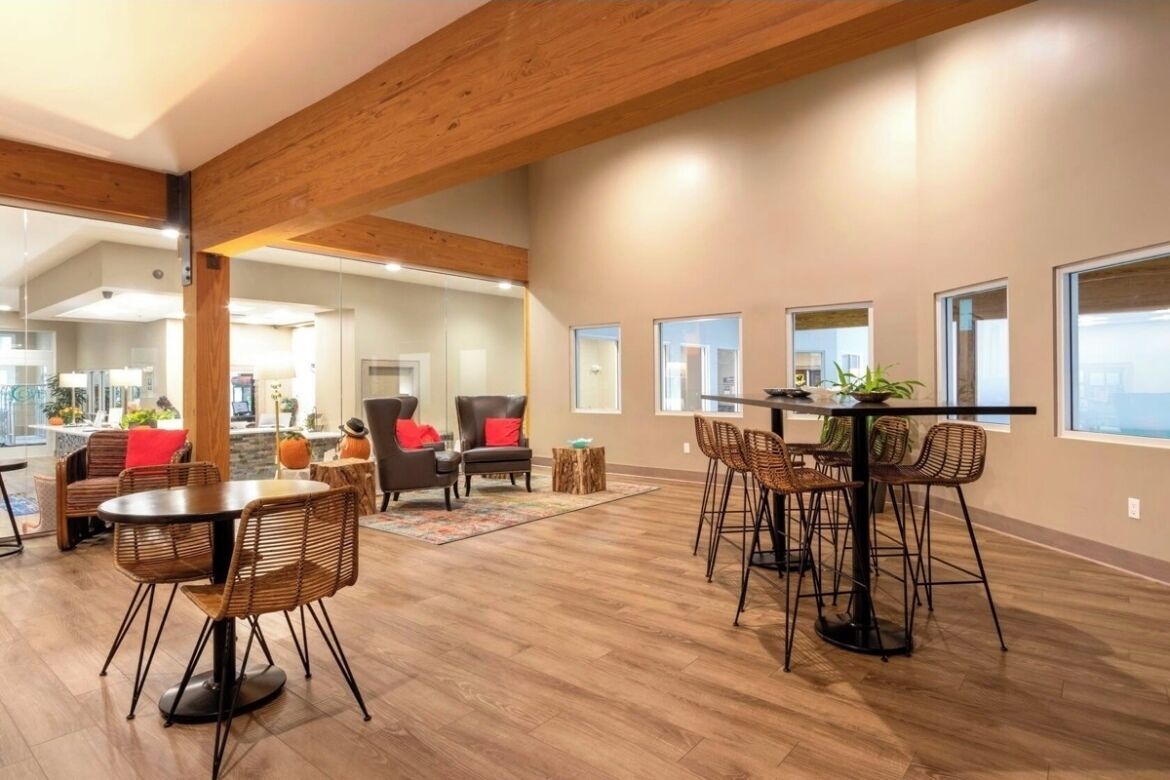 A spacious living area with a high ceiling, wooden beams, and a dining table with chairs.