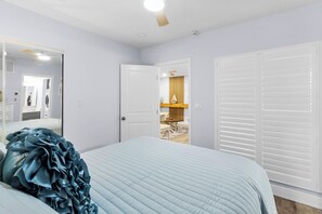 A bedroom with a bed, a wardrobe, a mirror, and a door leading to a bathroom. - Coastal Comfort at Madeira Beach Yacht Club #175A (Madeira Beach)