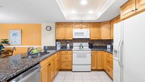 A modern kitchen with wooden cabinets, a stainless steel sink, a built-in oven, and a microwave. - Beach Front 3 Bedroom - Beach Place #507 (Madeira Beach)