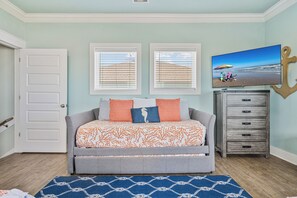 Een slaapkamer met een bed, een dressoir, een televisie en een deur.