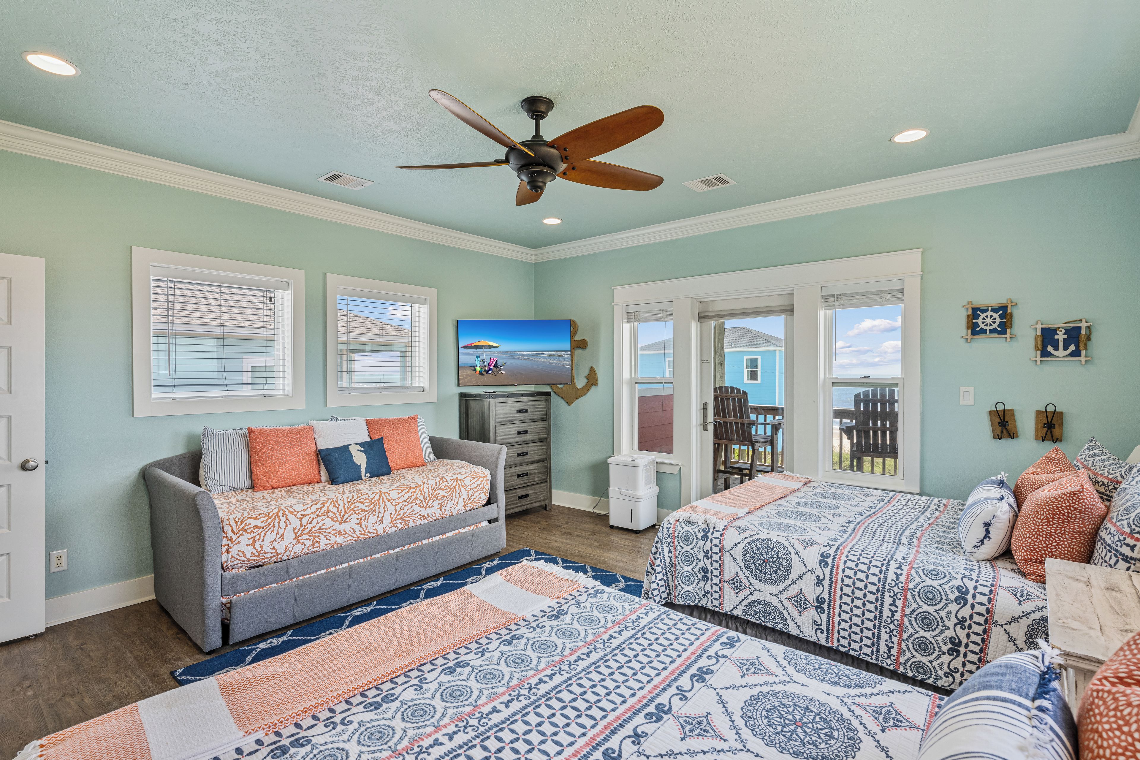 A room with a bed, a sofa, a ceiling fan, and a view of the outdoors.
