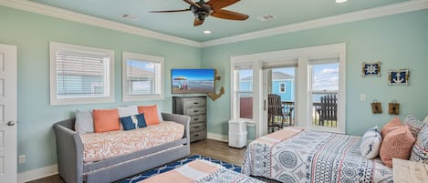 A room with a bed, a sofa, a ceiling fan, and a view of the outdoors.