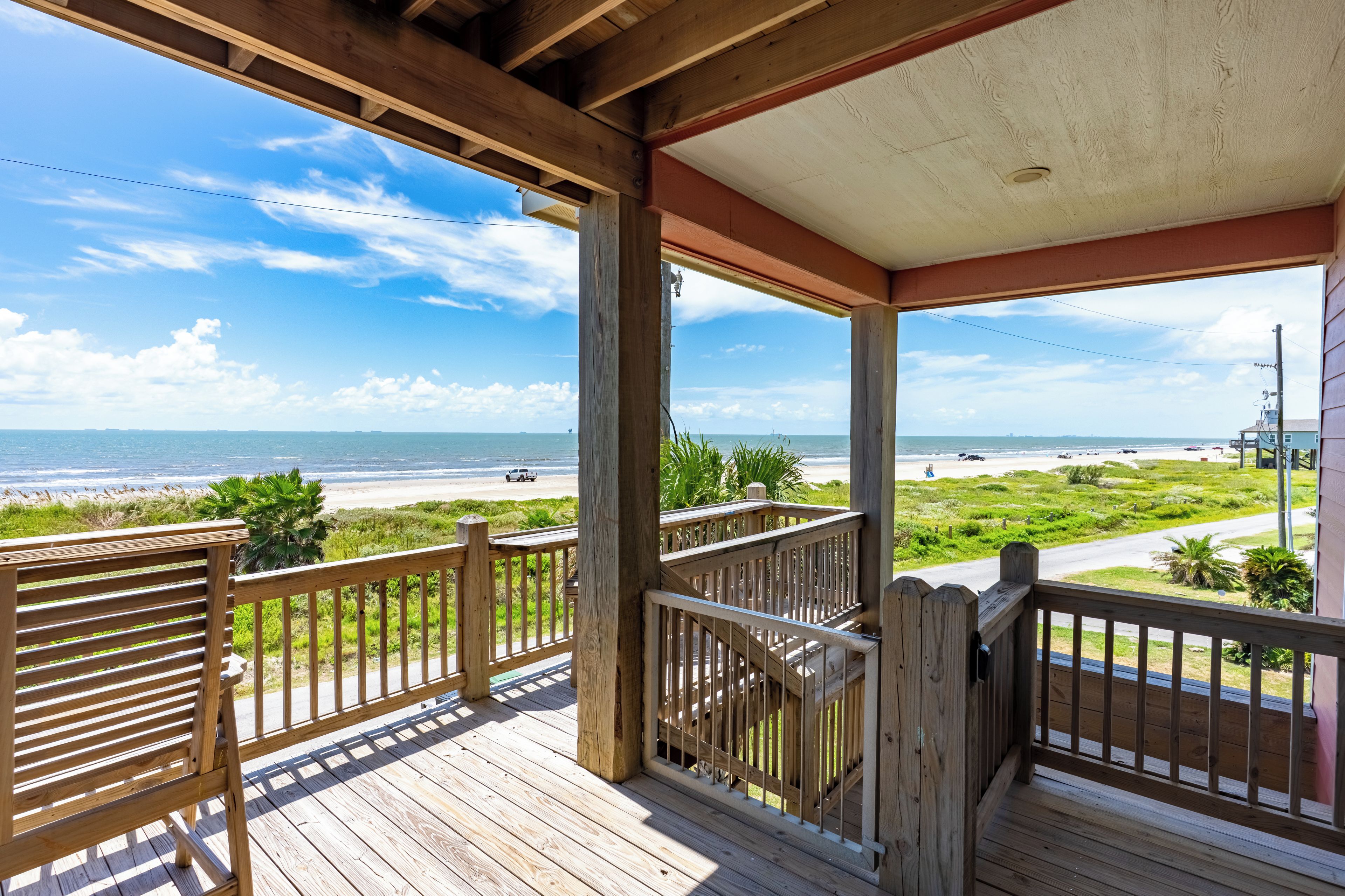 Une terrasse en bois offrant une vue sur la plage et l’océan.
