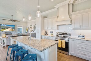 A spacious kitchen with a large island, white cabinetry, and a modern stainless steel range. - Easy Breezy! 4 bedroom 4 Bath, Direct Ocean view, easy beach access. (Crystal Beach)
