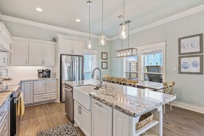 A modern kitchen with white cabinetry, a stainless steel refrigerator, and a marble countertop. - Easy Breezy! 4 bedroom 4 Bath, Direct Ocean view, easy beach access. (Crystal Beach)