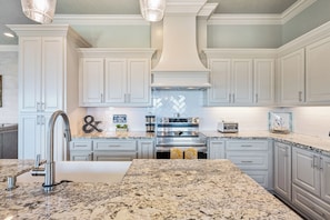 A kitchen with white cabinetry, a granite countertop, stainless steel appliances, and a decorative backsplash. - Easy Breezy! 4 bedroom 4 Bath, Direct Ocean view, easy beach access. (Crystal Beach)