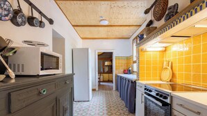 A kitchen with a microwave, refrigerator, stove, and tiled backsplash. - La villa  des pins (Agde)