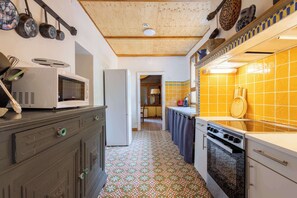 A kitchen with a microwave, refrigerator, stove, and tiled backsplash. - La villa  des pins (Agde)