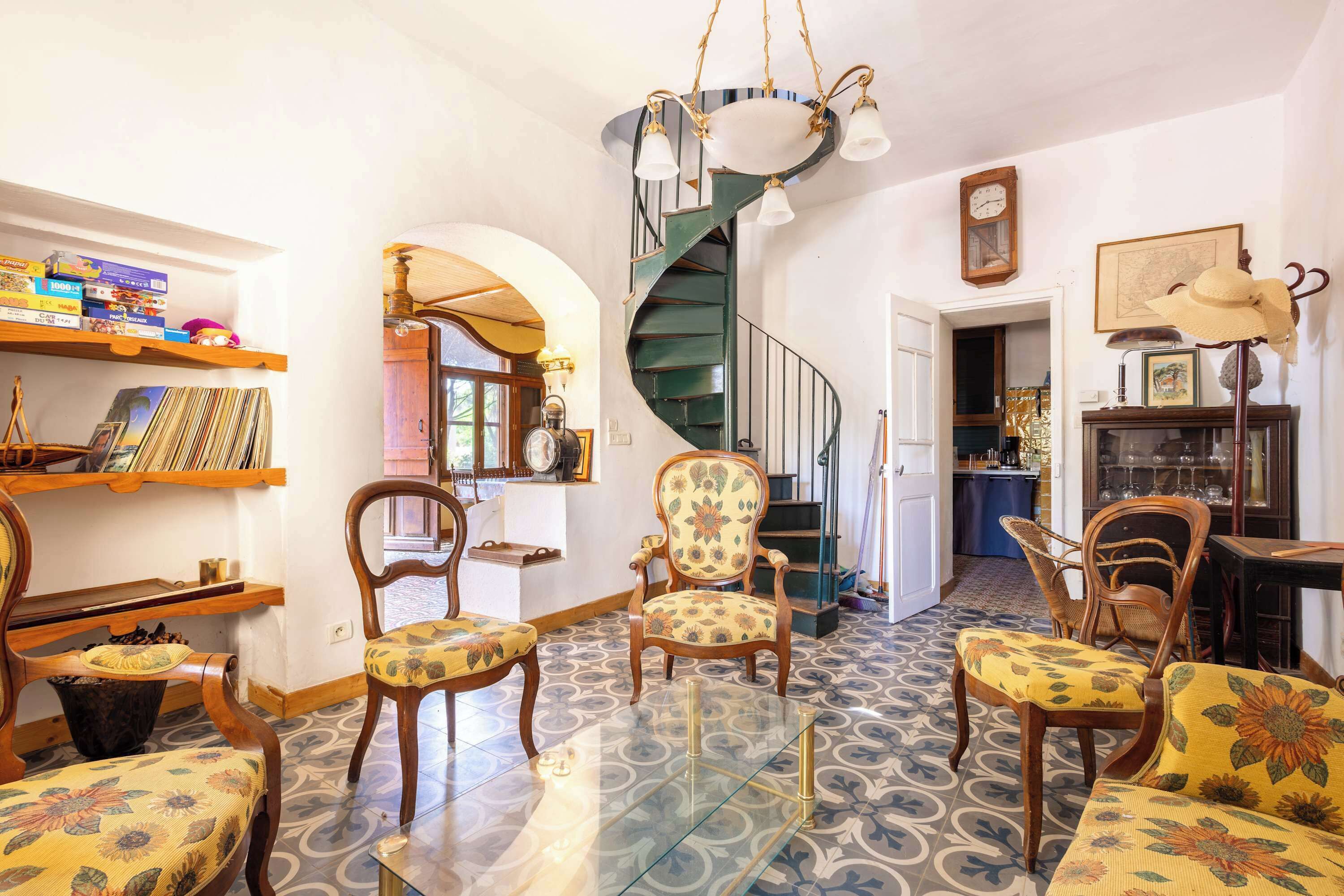 Una sala de estar acogedora con una escalera espiral, muebles de madera y una mesa de centro de vidrio.