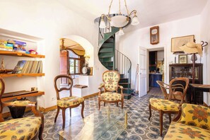 A cozy living room with a spiral staircase, wooden furniture, and a glass coffee table. - La villa  des pins (Agde)