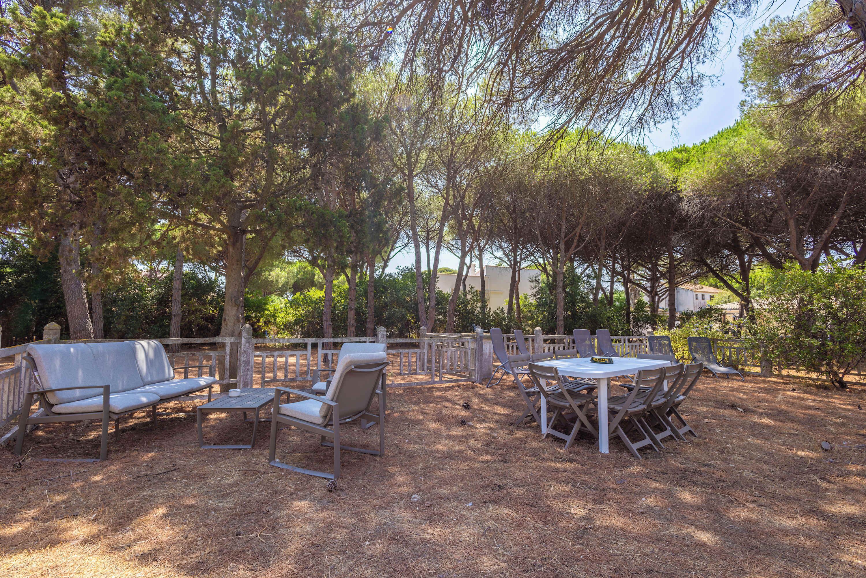An outdoor patio with a dining table and chairs, surrounded by trees.